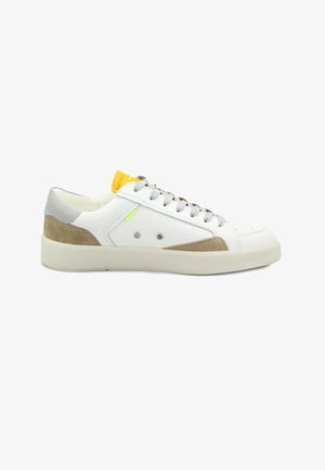 Witte lage sneaker met grijze veters, beige suède accenten, gele tong en ventilatieoogjes op een dikke witte zool.