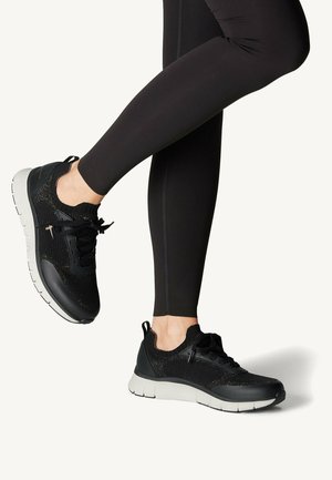 Black athletic shoes with a breathable mesh upper and cushioned sole, featuring laces and a textured finish. Paired with black leggings.