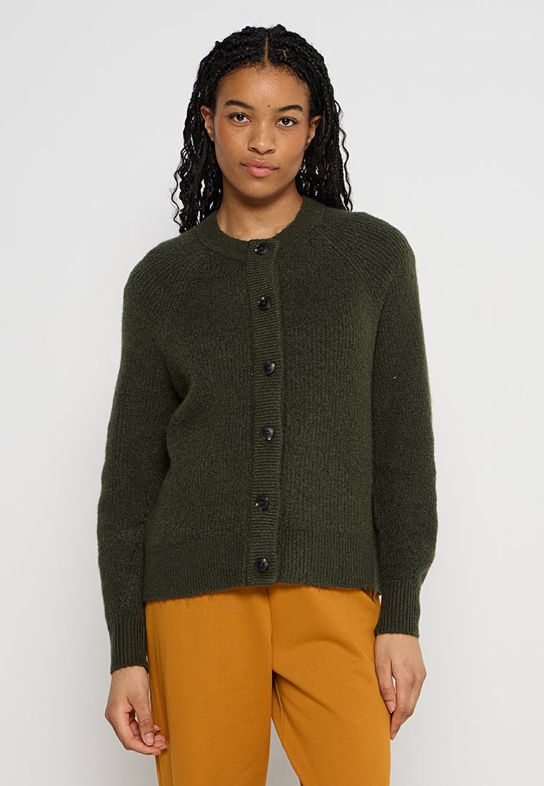 Donkergroen gebreide cardigan met een ronde hals, lange mouwen en een knoopsluiting. Heeft een ribbelstructuur en zwarte knopen.