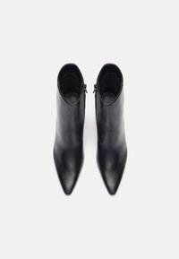 Bottes de cheville en cuir noir avec un bout pointu, au design épuré, et des fermetures éclair à l'arrière. Texture lisse sans motifs ou accents visibles.