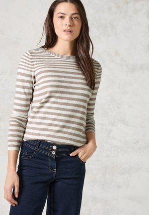Maglione a righe in beige e crema, scollatura tonda, maniche aderenti. Abbinato a jeans blu scuro con chiusura a due bottoni e tasche laterali.