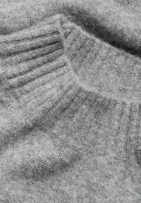 Grau gestrickter Pullover mit einem weichen, strukturierten Knit und einem gerippten, runden Ausschnitt, der ein gemütliches und warmes Material hervorhebt.