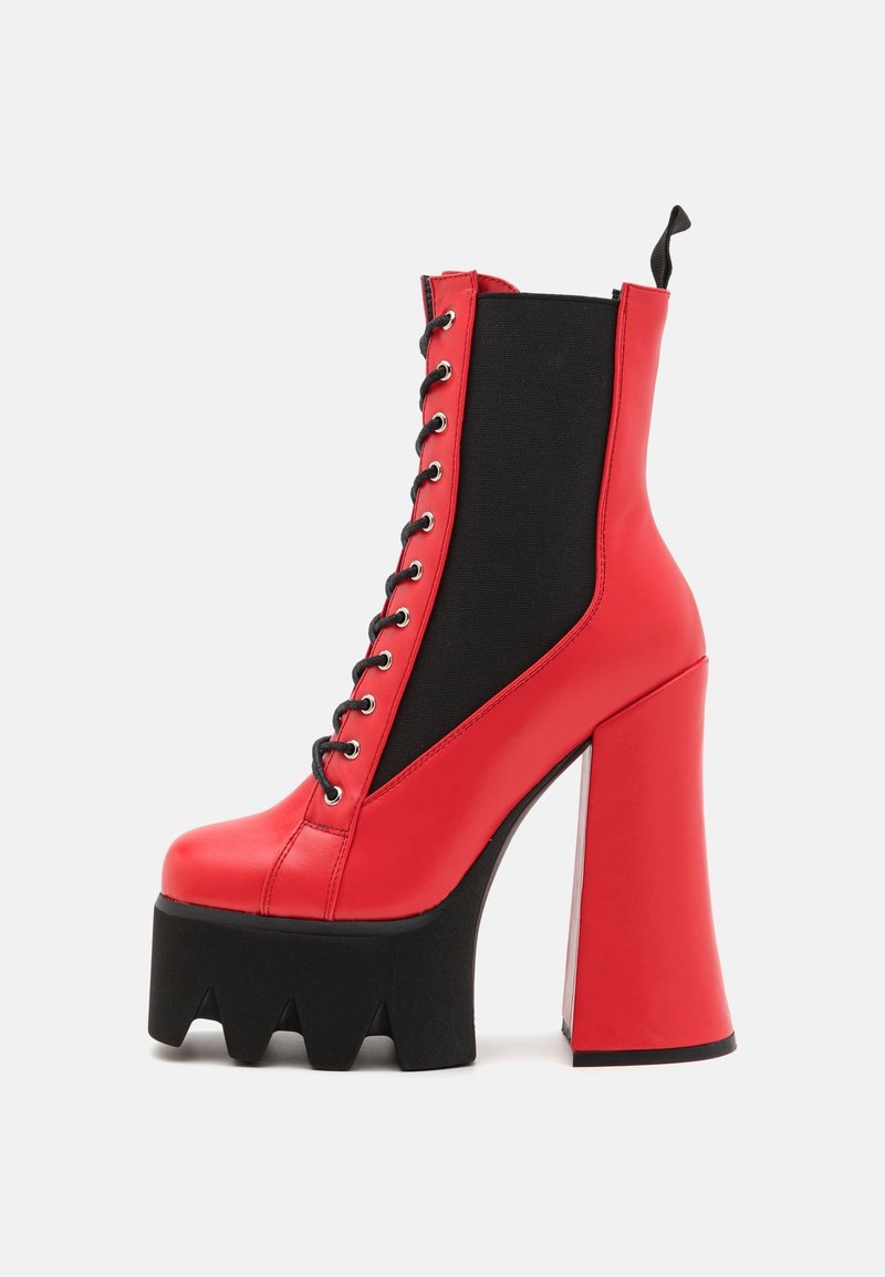 Botte plateforme rouge à lacets avec semelle crantée noire épaisse, talon bloc haut, et panneau latéral élastique noir, présentée sur un fond uni.