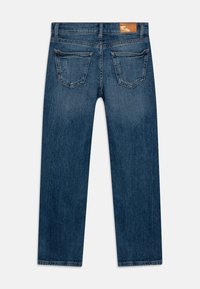 Vaqueros de denim de color índigo oscuro, diseño de pierna recta, dos bolsillos traseros y una etiqueta marrón en la cinturilla. Textura suave.