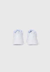 Witte Puma sneakers van achteren afgebeeld met gevoerde hakken en het logo op de hieltabs tegen een effen lichte achtergrond.