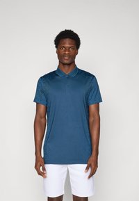 Navy blue polo shirt with a textured pattern on the shoulders, short sleeves, and a three-button placket; paired with white shorts.