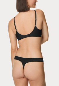 Ensemble de lingerie noire comprenant un soutien-gorge simple avec des bretelles réglables et un string assorti au design minimaliste et à la texture douce.