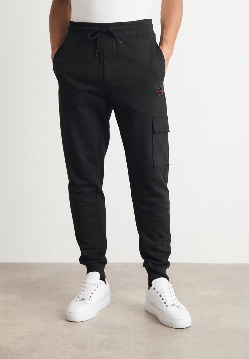 Svarta cargo sweatpants i mjukt tyg, med dragstring i midjan, sidofickor och en sidoficka. Parat med vita sneakers.