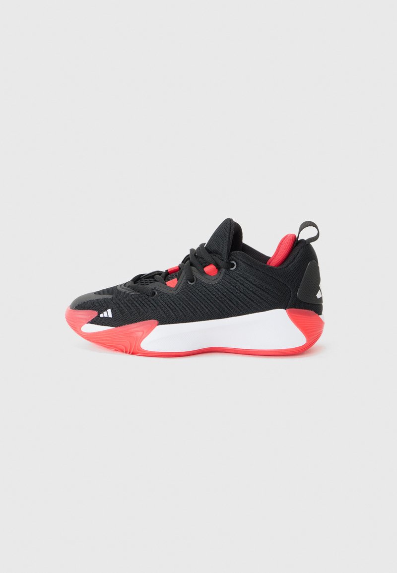 Chaussure de sport noire avec un dessus texturé, des accents rouges, une semelle intermédiaire blanche et une semelle en caoutchouc rouge. Comprend des lacets et une languette au talon.