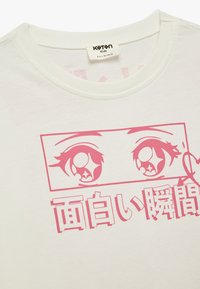 Camiseta de algodón blanca con un gráfico rosa de ojos estilizados y texto en japonés. Cuello redondo con una textura suave.