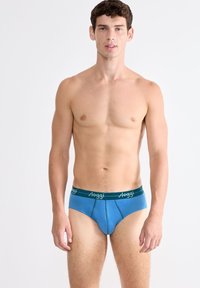 Blaue Unterhose mit grünem Bund und weißem Logotext. Glattes Material, taillierte Passform und kontrastierende Nähte.