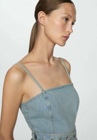Denimmekko vaaleansinisena, rakenteellinen muotoilu ohuiden olkaimien kanssa, suora pääntie, näkyvät saumat ja metalliset yksityiskohdat vyötäröllä.