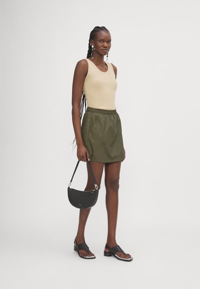 Beige ribbed tank top, olive green elastic waist skirt, black curved handbag, and black sandals with a slight heel and white accents.