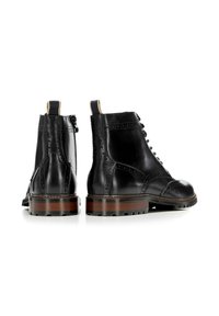 Botas de cuero negras con detalles de brogue, cordones en la parte delantera, pequeña lengüeta de tirón y una suela de madera robusta con un acabado texturizado.