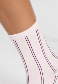 Różowa skarpetka z prążkiem w kolorze bordowym i jasnoniebieskim, w pionowe paski, wykonana z miękkiego, teksturowanego materiału, z wygodnym mankietem.