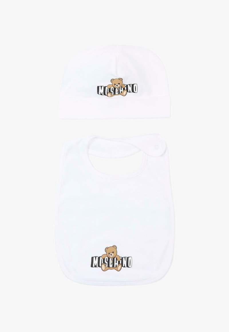 Conjunto de gorro y babero blancos para bebé, cada uno con un osito de peluche marrón y el texto "Moschino" en negro y blanco detrás.