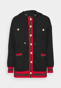 Sudadera negra con capucha, botones dorados, rayas rojas y verdes, bolsillos delanteros y una silueta relajada. Material suave y diseño casual.