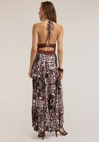 Abito maxi multicolore con scollo all'americana, schiena scoperta e intricati motivi floreali in bordeaux e nero su sfondo crema.