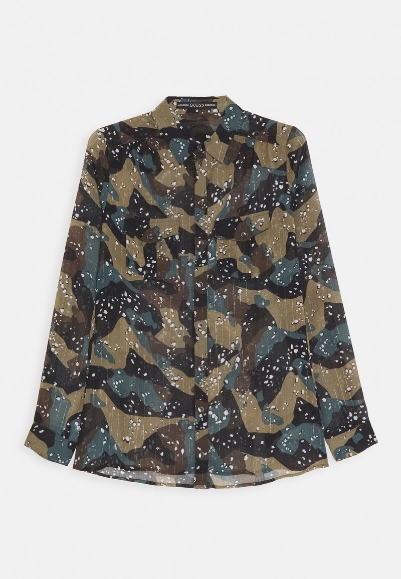 Chemise camouflage à manches longues avec des motifs verts, bruns et noirs et des taches blanches, dotée de poches poitrine boutonnées et d'un col.