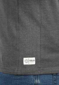Mørkegrå bomuld t-shirt synlig, med lige snit, synlige sømme og et mærketikette i nederste venstre hjørne.