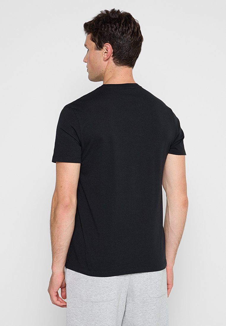 Zwart katoenen T-shirt, korte mouwen, ronde hals, zachte textuur, slim fit, gedragen met grijze sweatpants. Zicht vanuit de achterkant.