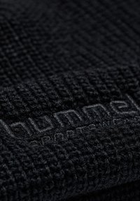 Il tessuto nero testurizzato presenta un motivo intrecciato, con un marchio sottile visibile in una tonalità di nero più scura, che esalta la profondità del materiale.