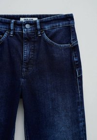 Jean denim bleu foncé de la taille jusqu'à mi-cuisse avec poches avant visibles, bouton et étiquette portant la mention "Salsa Jeans."