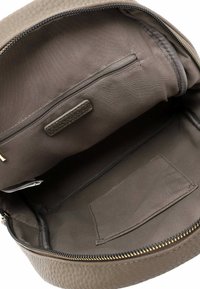 Pruun tekstuuriga nahkbackpack, millel on üks tõmblukuga sektsioon, sisaldades siledat, vooderdatud sisemust ja täiendavat tõmblukuga taskut.