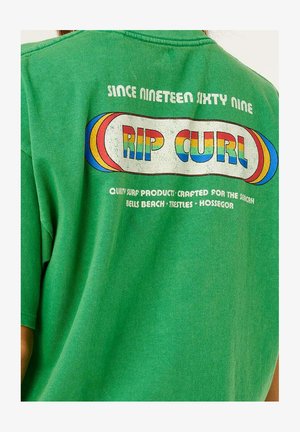 Grünes Hemd mit mehrfarbigem Schriftzug "RIP CURL", "Seit Neunzehnhundertneunundsechzig" und Surfspots Bells Beach, Trestles, Hossegor.