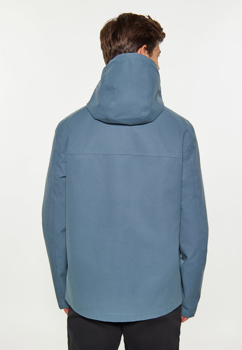 Veste imperméable bleu clair avec capuche, présentant une texture lisse, un ourlet droit et des coutures piquées. Le design est simple et fonctionnel.