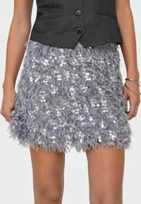 Pelēks pūkains svārks ar spīdumiem, ar teksturētu, slāņainu dizainu un izplestu formu, kas beidzas virs ceļa.