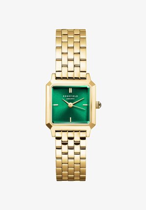 Montre-bracelet en métal doré avec un cadran carré vert, présentant des index horaires, des aiguilles dorées et une surface texturée. Nom de la marque affiché.