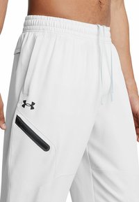 Weiße sportliche Jogginghosen aus leichtem Material, mit elastischem Bund, Kordelzug und einer Reißverschlusstasche mit schwarzem Besatz.