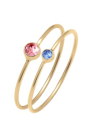 To tynde guldringe med kantsatte runde ædelsten, en lyserød og en blå, vist på en hvid baggrund.