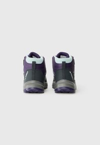 Un paio di scarpe da trekking Adidas Terrex viola e grigio viste da dietro su uno sfondo bianco.