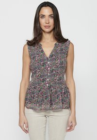 Blusa floreale con scollo a V, senza maniche, in colori pastello e piccoli bottoni lungo la parte anteriore. Presenta un orlo peplum arricciato.