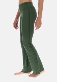 Ciemnozielone spodnie rozszerzane z wysokim stanem i falistym wykończeniem po bokach. Wykonane z gładkiego, elastycznego materiału, zaprojektowane z myślą o komforcie.