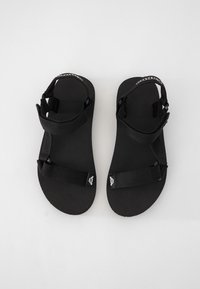 Svarta sandaler med en strukturerad fotbädd, med två justerbara remmar och en tredje rem över vristen för stöd.