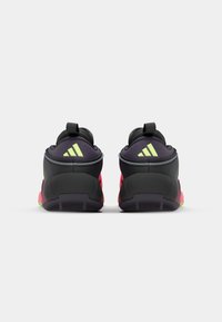 Scarpe da ginnastica nere e rosa con una finitura testurizzata, dotate di un collare imbottito, un manico per il pull e dettagli fluorescenti verdi sulla suola.