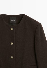 Dark brown coat with a textured finish, featuring a round neckline, five metallic buttons, and a front pocket. Label visible inside.