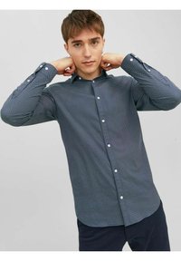 Camicia blu con bottoni, con piccoli pois bianchi, maniche lunghe e polsini regolabili. Fit slim con colletto standard e texture liscia.