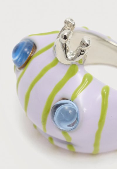 Χοντρό δαχτυλίδι με βάση λεβάντας, πράσινες κάθετες ρίγες, δύο διάφανα μπλε χάντρες και ασημένια λεπτομέρεια σε σχήμα κορώνας στην κορυφή.