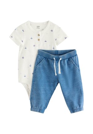 Valkoinen vauvan body, jossa on pieniä sinisiä purjelaivaprinttejä ja puiset napit, yhdistetty sinisiin joustavyötäröisiin jogger-housuihin, joissa on kiristysnauha.