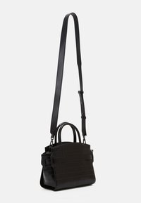 Černá texturovaná kožená taška s dvěma krátkými uchy a jedním dlouhým nastavitelným ramenním popruhem, umístěná na čistém bílém pozadí.