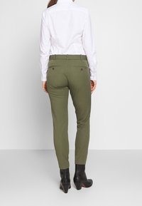 Olivgröna skräddarsydda byxor med slim fit, med bakfickor som stängs med knappar och en jämn, vävd textur.