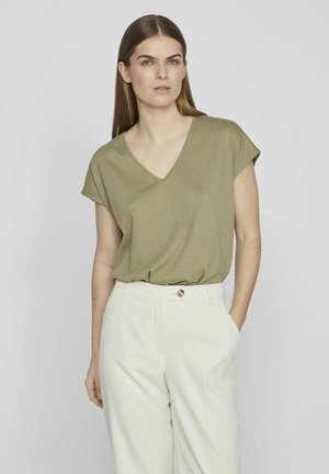 Olivenfarbener V-Ausschnitt-T-Shirt mit kurzen Ärmeln, entspannter Passform und weicher Textur, kombiniert mit hochgeschnittenen hellbeigen Hosen.