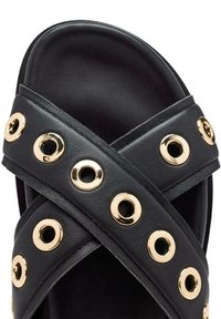 Sandal in pelle nera con cinghie incrociate e accenti circolari dorati. Texture liscia con un design ampio e aperto per le dita dei piedi.