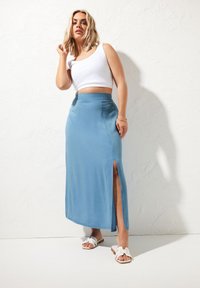 Ljusblå knälång kjol i mjukt material, med en hög slits på ena sidan och en åtsittande midja. Matchad med en vit kortärmad linne.