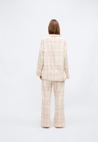 Lysfarget rutete pyjamassett laget av mykt stoff; har en langermet topp med krage og matchende, løstsittende bukser.