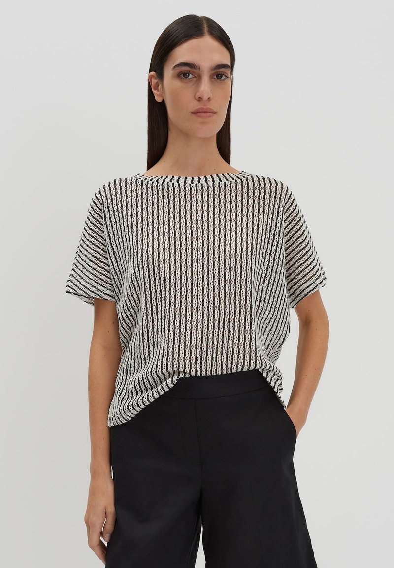 Zwart-wit gestreepte korte mouw top, lichte geweven stof, brede halslijn, losse pasvorm, gecombineerd met zwarte broek.